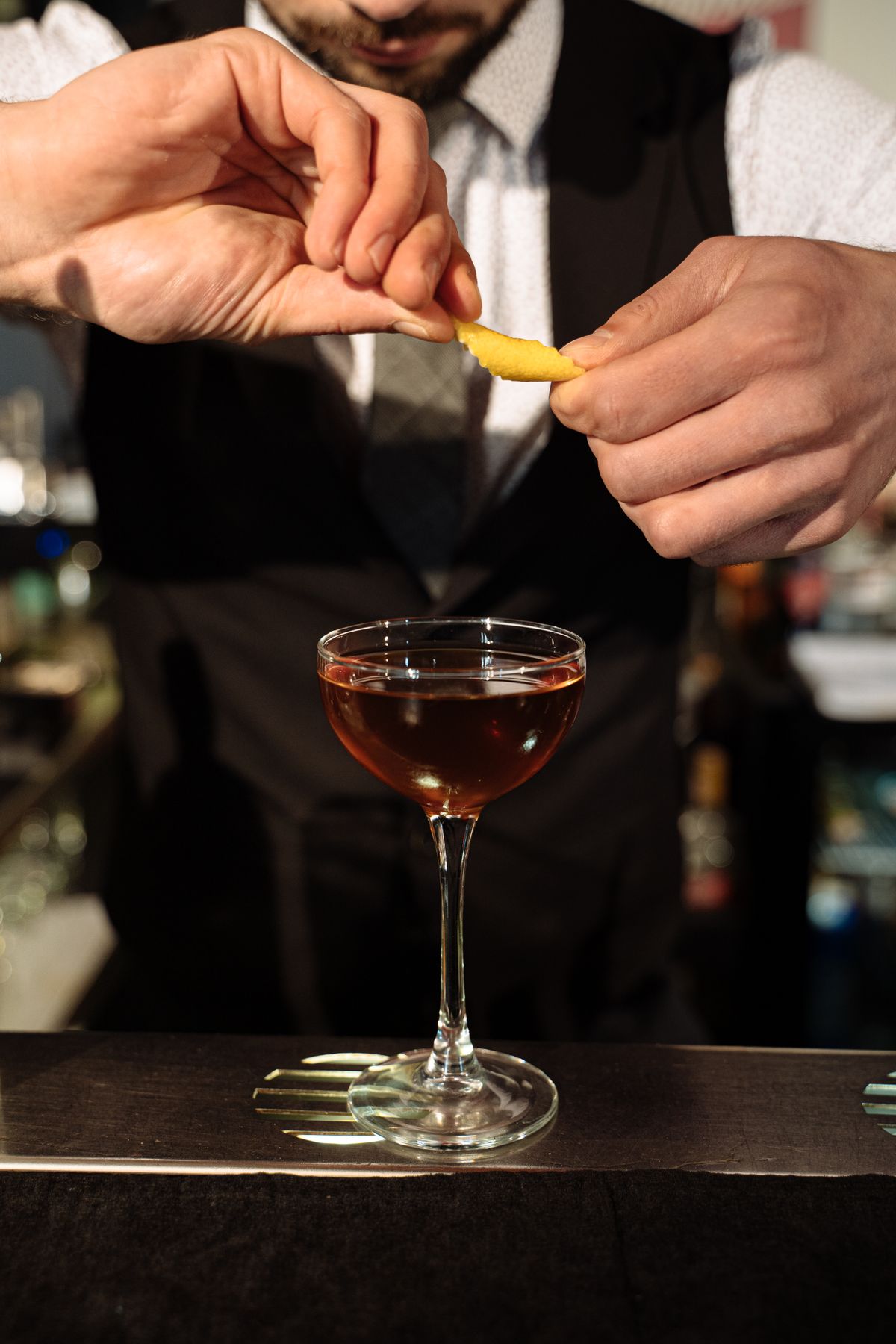 Bartender finishing a cocktail with a citrus zest